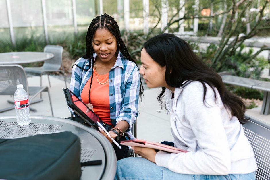 A diverse group of engaged students collaborating around a tablet device in a bright, modern classroom, illustrating the successful integration of educational technology.